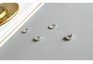 Nahaufnahme minimalistischer S925 Sterlingsilber Creolen auf einer dekorativen Goldplatte
