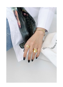 Detail von gehämmerten Goldarmbändern und Ringen mit Lavatextur im Lifestyle-Design