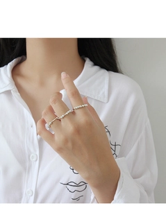 Anelli minimalisti in argento S990 con perline indossati su sfondo camicia bianca