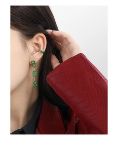 Detail of green enamel twisted earrings and ear cuff on model with red leather jacket