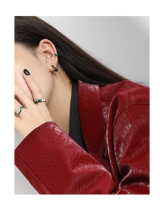 Close-up of model wearing green enamel earrings and rings with twist texture detail
