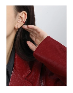 Detail of red enamel ear cuff and silver hoop earring on ear with red jacket