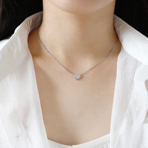 Collier avec pendentif cœur minimaliste en argent S925 sur un mannequin en chemise blanche