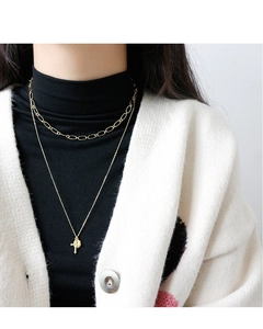 Close-up of layered gold necklace with cross pendant on black turtleneck clothing