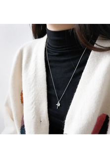 Detailed view of S925 silver necklace with cross and disc pendant on black turtleneck
