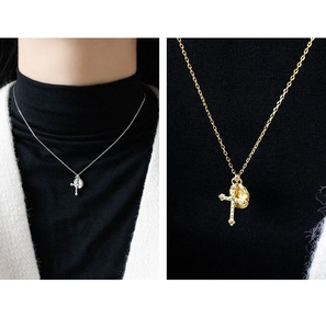 Detail of silver and gold cross and lava pendants on a long delicate chain necklace