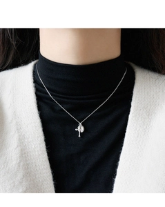 Close-up of S925 sterling silver necklace with cross and round disc pendants on black top