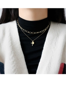 Close-up of double-layered gold necklace with cross and medallion on a model