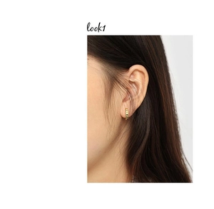 Close-up of gold textured hoop earrings featuring vertical grooves on a female model