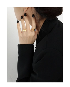 Close-up of minimalist gold ring and studs with grey round stones on a model