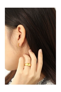 Detailed view of polished golden hoop earring and thick dome ring on female model