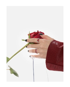 Primer plano de un anillo con gema roja de corazón y banda de plata en la mano