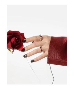Detalle de los anillos de plata líquida con piedras rojas sobre fondo de rosas rojas