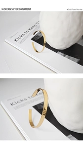 Detail view of a minimalist gold-plated open bangle with a polished mirror finish