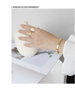Polished gold bangles and rings with coin relief and hammered texture on woman's hand