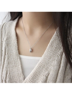 Gros plan d'un pendentif haricot en argent sterling S925 poli sur une chaîne minimaliste