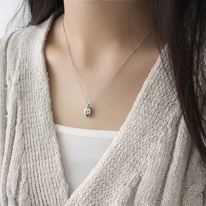 Collier minimaliste en argent S925 avec pendentif grain de café porté par un mannequin