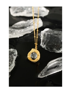 Gros plan détaillé d'un collier doré texture lave avec un cristal de pierre de lune