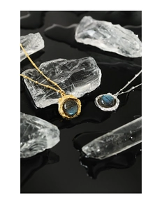 Détail du collier en labradorite avec texture de lave sur une surface miroir noire