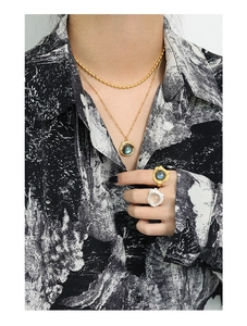 Gros plan sur collier de perles dorées et pendentif labradorite avec bague cristal