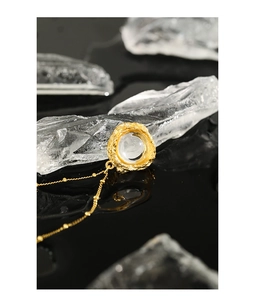 Détail du pendentif en texture de lave dorée avec pierre de lune sur miroir noir