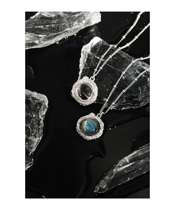 Détail du collier argenté avec pendentif texture lave, labradorite et cristal blanc