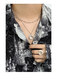 Détail du collier à texture de lave argentée et de la bague en cristal sur un mannequin