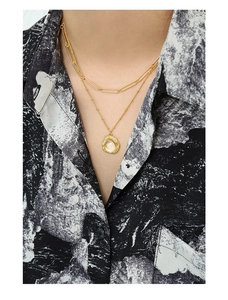 Détail du collier double rang doré avec chaîne trombone et pendentif texture lave