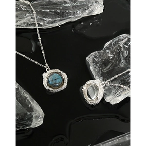 Colliers pendentifs texture lave avec labradorite et cristal blanc sur reflet d'eau