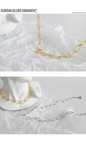 Detail von minimalistischen Gliederketten in Gold und Silber auf weißem Hintergrund