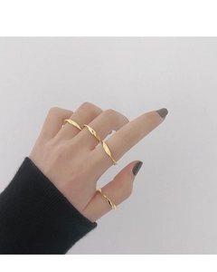 Primer plano de anillos Mobius dorados minimalistas en los dedos para un look en capas
