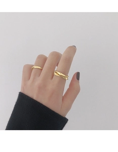 Primer plano de un anillo giratorio Mobius dorado y un anillo fino en el dedo