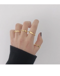 Detalle de cuatro anillos dorados con ondas en la mano sobre fondo de punto negro