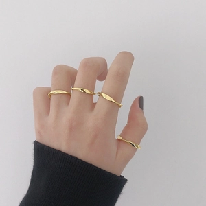 Set de cuatro anillos Mobius minimalistas dorados lucidos por una modelo sobre fondo gris