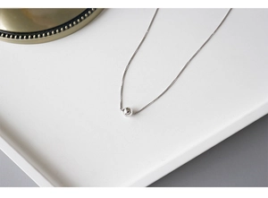 Close-up of a S925 sterling silver box chain necklace with a polished sphere pendant