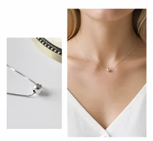 Detailed close-up of polished S925 sterling silver ball pendant and dainty chain necklace
