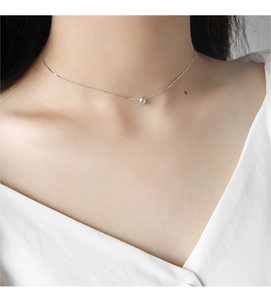 Close-up of minimalist S925 sterling silver choker necklace with polished round bead pendant