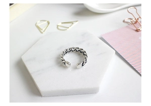 Detail of vintage silver chain ring displayed on a marble textured exhibition board