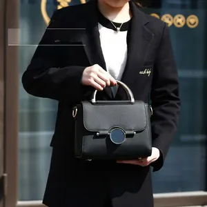 Detail of black pebbled leather handbag with unique semi-circle metal handle and magnetic clasp