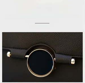 Macro detail of polished gold round buckle on brown litchi pattern cowhide leather bag