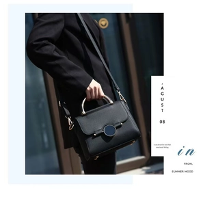 Detail of black pebbled leather crossbody bag with golden ring buckle and D-ring hardware