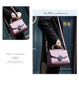Detail of purple crossbody bag with leather lychee texture and round metal buckle