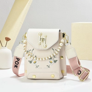 Detalle de bordado floral y cadena de perlas en bolso vertical crema para teléfono móvil