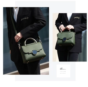 Detail of dark green pebble leather bag with gold circular lock and metal handle