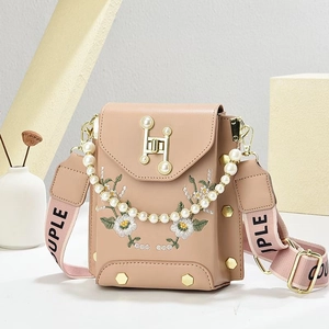 Detalle de margarita bordada en bolso de móvil rosa con asa de perlas y correa ancha