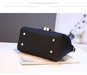 Detail view of black faux leather bag bottom with four protective gold metal feet studs