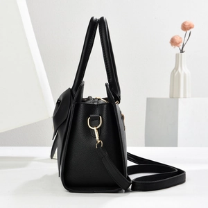 Detail der schwarzen Handtasche aus Leder mit Schleife und goldener Hardware