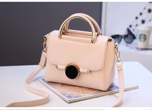 Detail of lychee pattern leather bag with gold ring handle and magnetic buckle closure