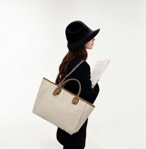 Detail of elegant large tote bag in off-white tweed with brown leather straps and metal chain
