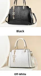 Detail of elegant black and off-white handbags with glossy crocodile texture and gold charms